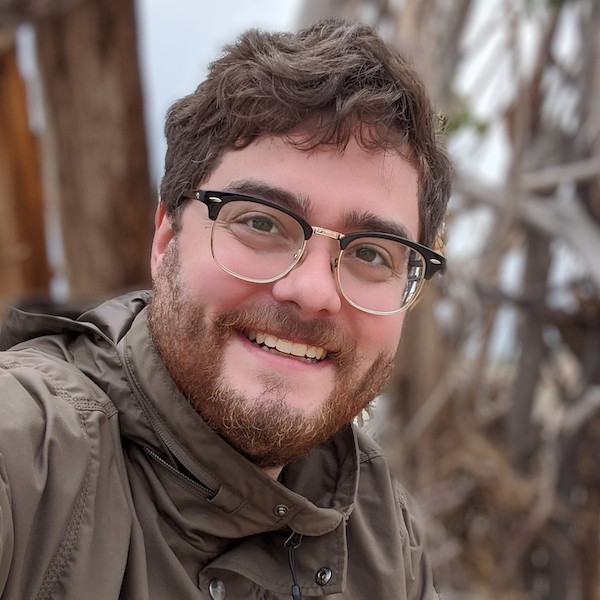 School of Information Sciences alum Dave Moore has short wavy brown hair and is wearing glasses and a wide smile. He is pictured in an outdoor setting and is wearing a Carhartt jacket.