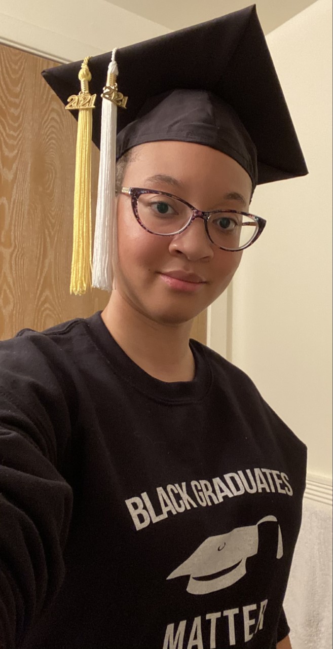 Amber Harrison is a black woman with short cropped hair. She wears a graduate cap with Class of 2021 tassels