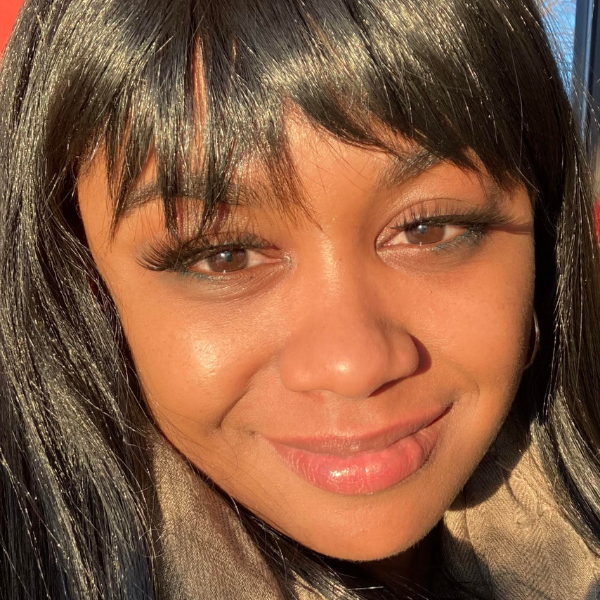SIS alumna Allia McCoy is a young woman of color with side swept bangs and a shy smile.