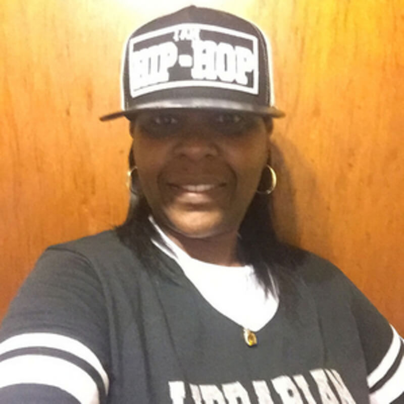 Joquetta Johnson wearing a gray hat with the words Hip Hop and a gray long-sleeved with the word Librarian across the front